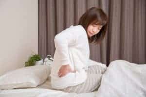 寝起きの腰の痛みを抱える女性